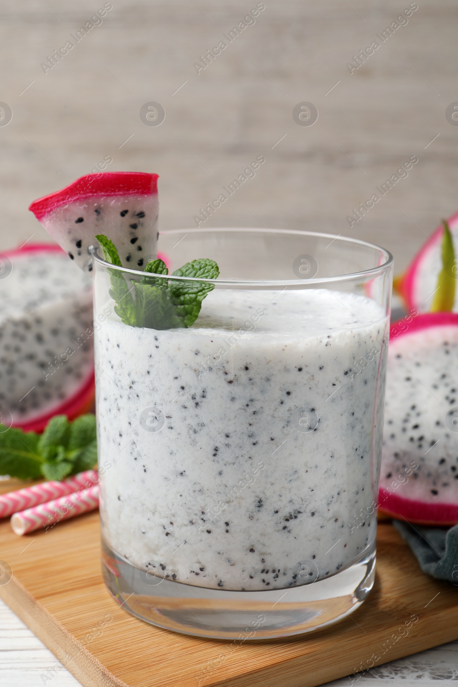 Photo of Glass of tasty pitahaya smoothie with fresh mint on white wooden table, closeup