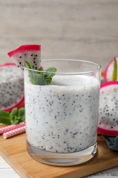 Photo of Glass of tasty pitahaya smoothie with fresh mint on white wooden table, closeup