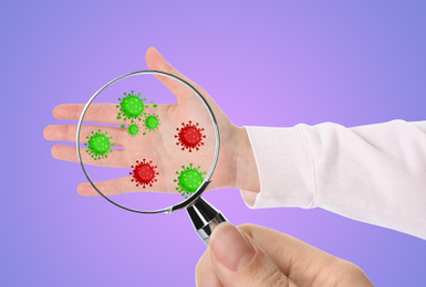 Image of Woman detecting bacteria with magnifying glass on lilac background, closeup. Prevention disease