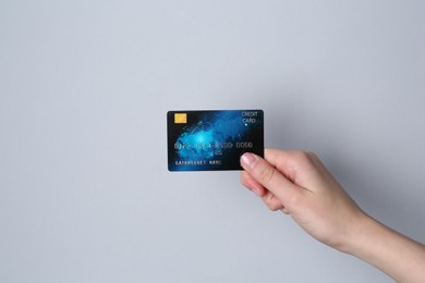 Woman holding credit card on light grey background, closeup