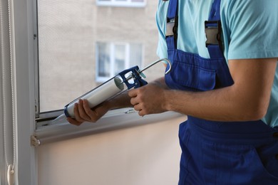 Construction worker sealing window with caulk, closeup