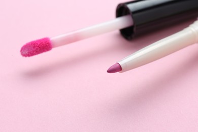 Photo of Lip pencil and brush of liquid lipstick on pink background, closeup. Cosmetic products