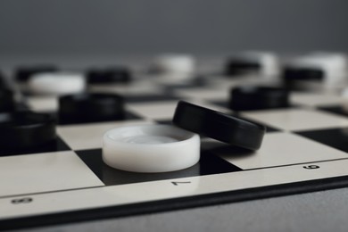 Photo of Checkerboard with game pieces on light grey background, closeup