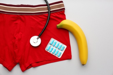 Photo of Flat lay composition with men's underwear and banana on light background. Potency problem concept