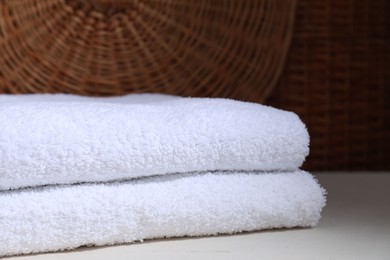 Photo of Stacked terry towels on white table, closeup. Space for text