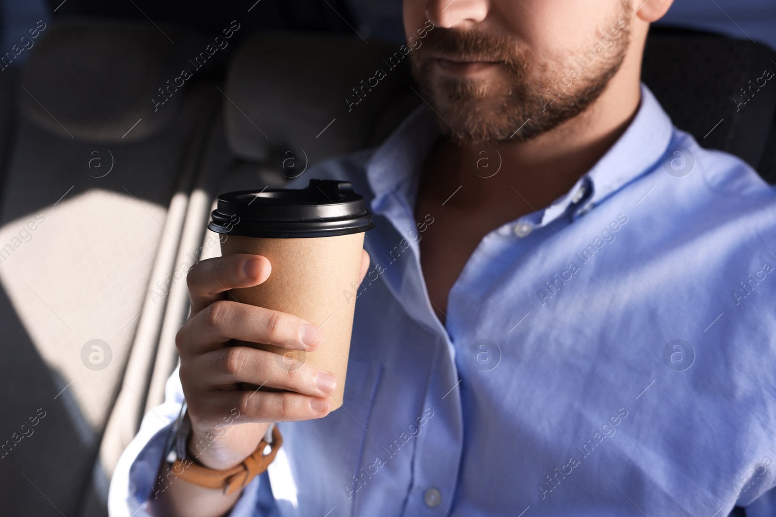 Photo of Coffee to go. Man with paper cup of drink in car, closeup