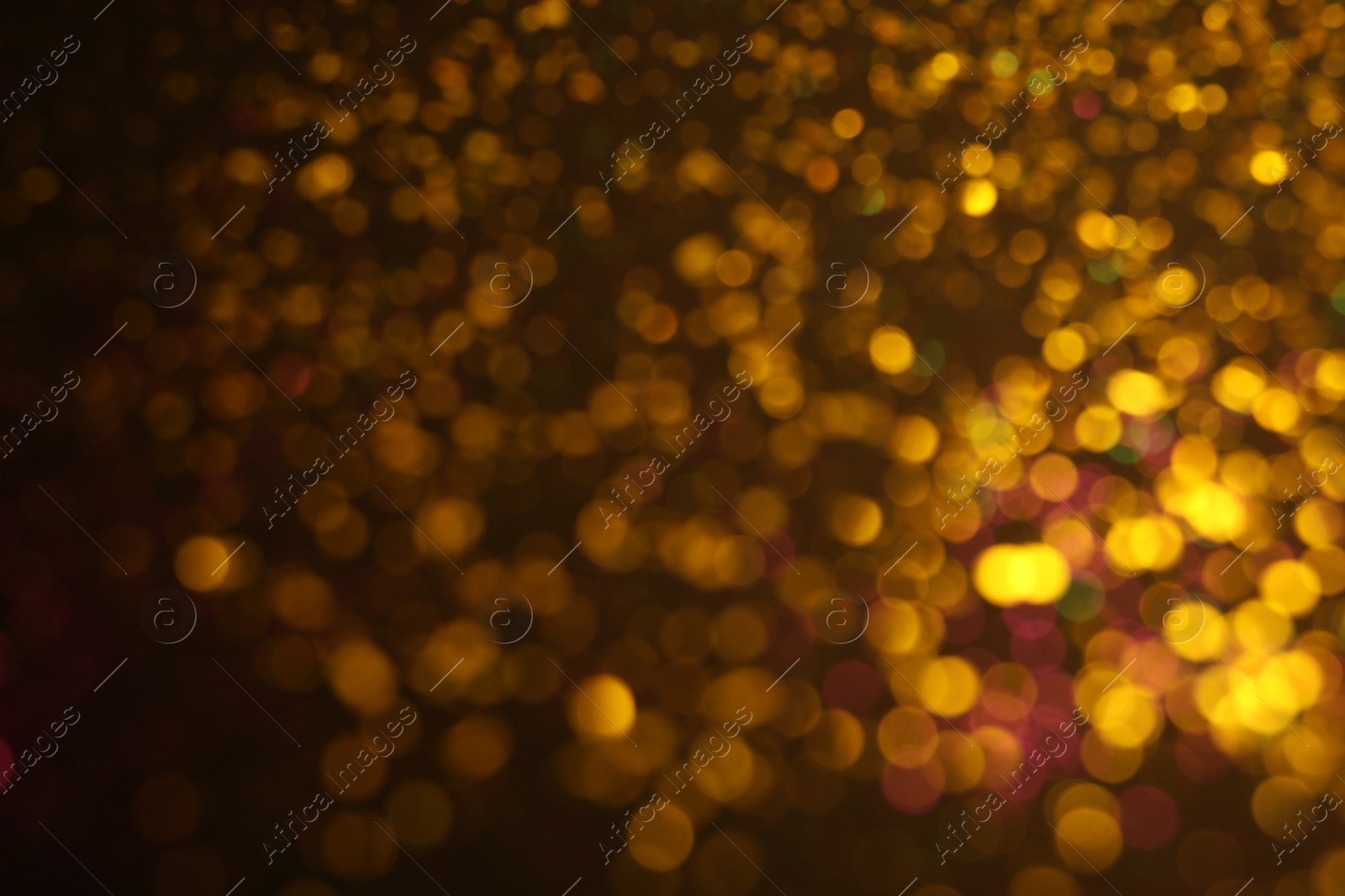 Photo of Blurred view of golden glitter on dark background. Bokeh effect