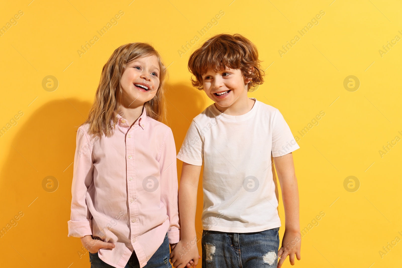 Photo of Fashion concept. Stylish children posing on yellow background