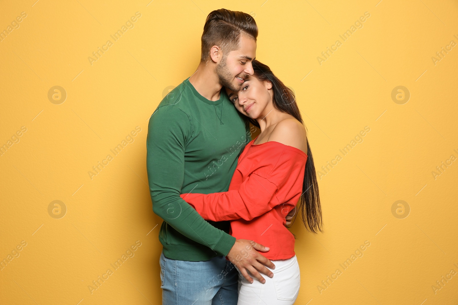 Photo of Young happy couple in trendy clothes on yellow background