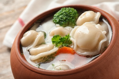 Photo of Pot of tasty dumplings with broth and vegetables on table, closeup