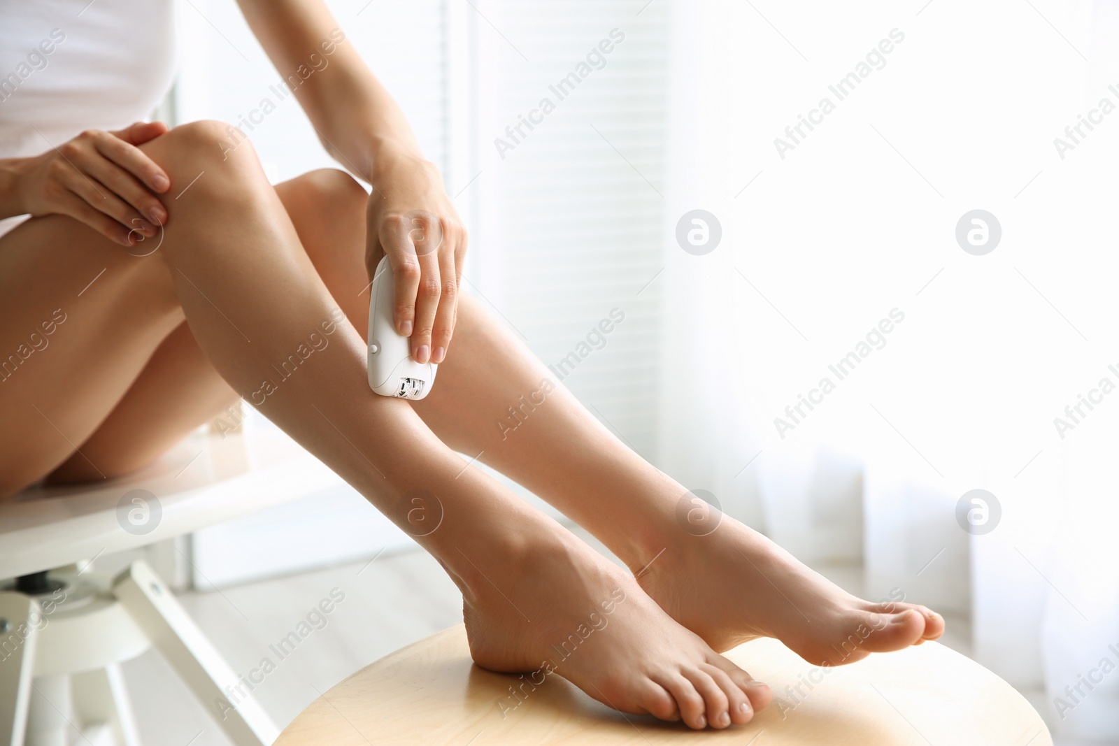 Photo of Woman doing leg epilation procedure at wooden table indoors, closeup