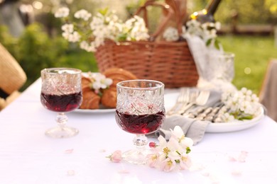 Stylish table setting with beautiful spring flowers, wine and croissants in garden