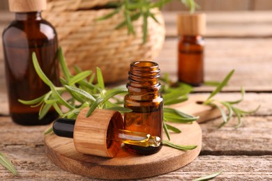 Aromatic essential oils in bottles, pipette and rosemary on wooden table, closeup