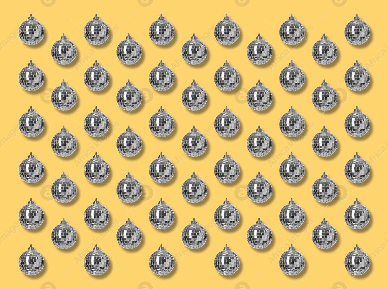 Image of Many shiny disco balls on yellow background, flat lay