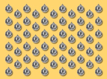 Image of Many shiny disco balls on yellow background, flat lay