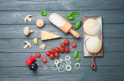 Photo of Dough and ingredients for pizza on wooden background, top view