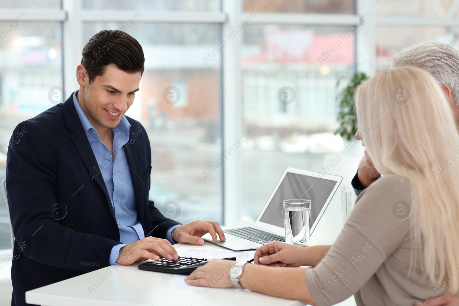 Photo of Mature couple discussing pension with consultant in office