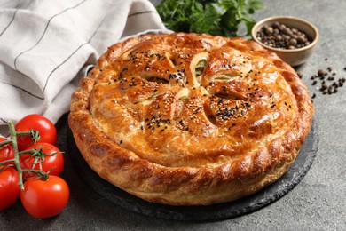 Photo of Tasty homemade pie, spices and fresh tomatoes on grey table