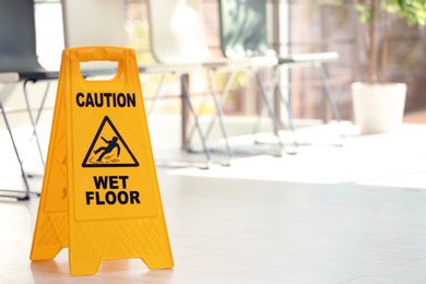 Safety sign with phrase Caution wet floor, indoors. Cleaning service