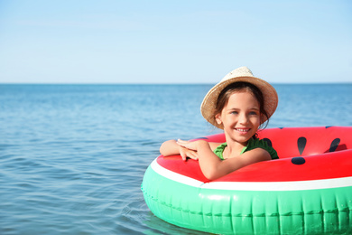 Photo of Cute little child with inflatable ring in sea on sunny day. Beach holiday
