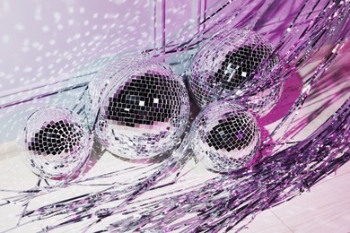 Photo of Shiny disco balls and foil fringe curtain indoors, color toned