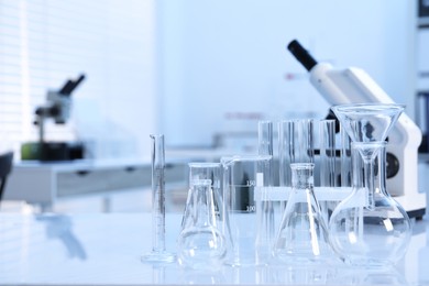 Photo of Laboratory analysis. Different glassware and microscope on white table indoors, space for text