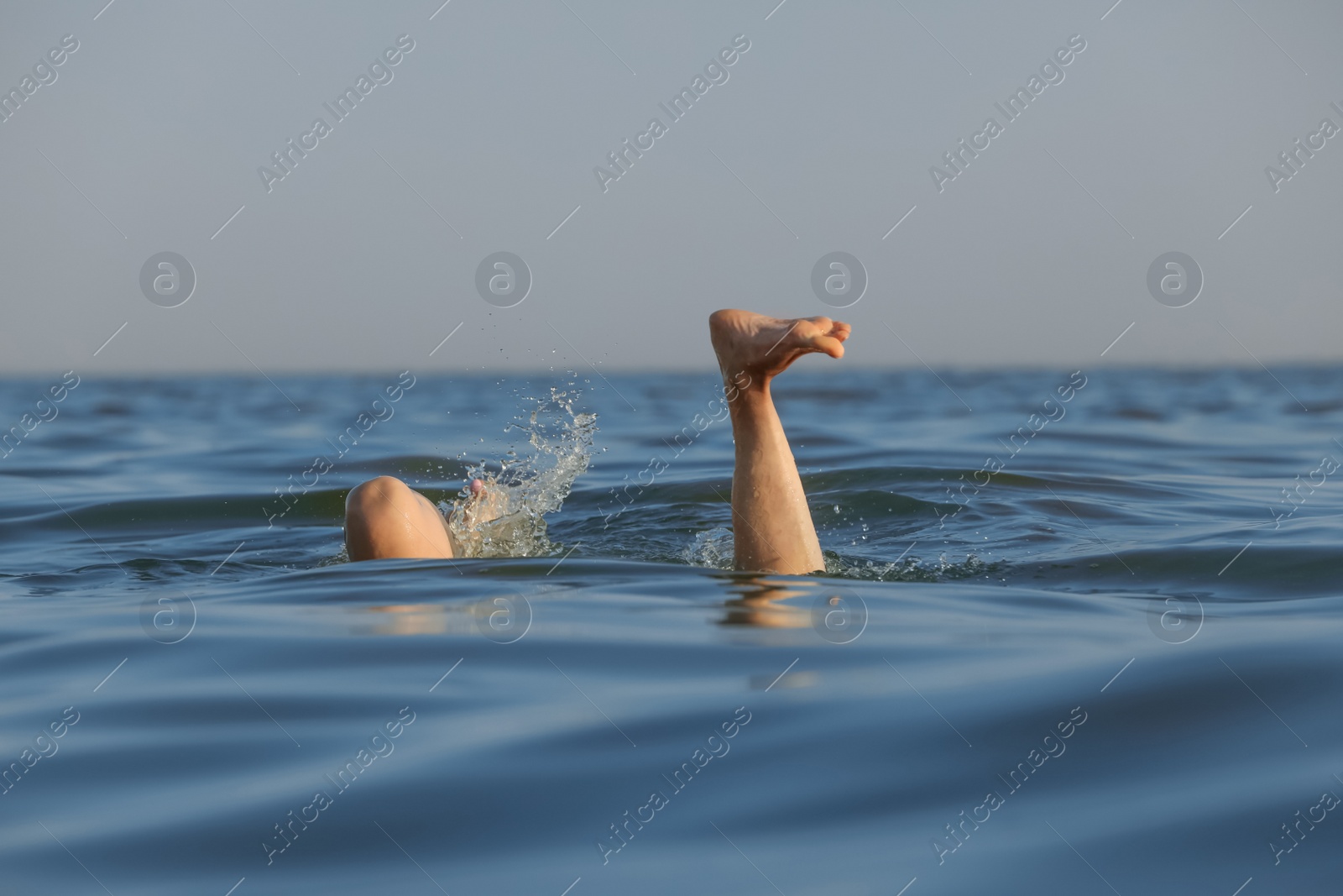 Photo of Drowning woman's legs sticking out of sea