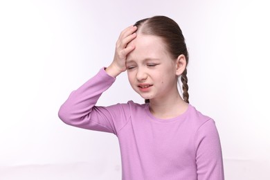 Photo of Little girl suffering from headache on white background