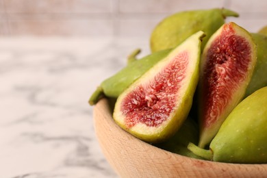 Photo of Cut and whole green figs in wooden bowl on table, closeup. Space for text