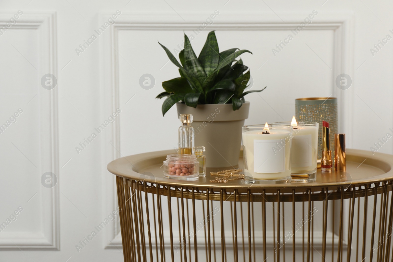 Photo of Burning soy candles, cosmetics and stylish accessories on table indoors. Space for text
