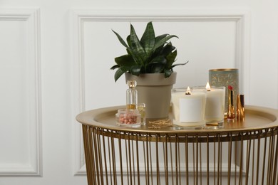 Burning soy candles, cosmetics and stylish accessories on table indoors. Space for text