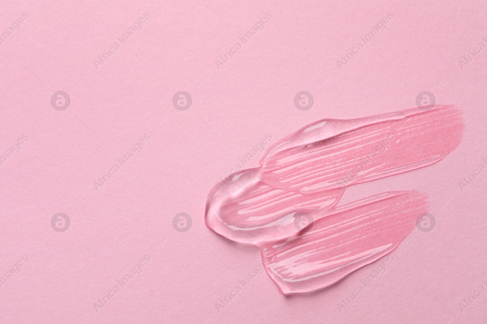 Photo of Swatches of cosmetic gel on pink background, top view. Space for text