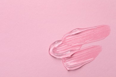 Photo of Swatches of cosmetic gel on pink background, top view. Space for text