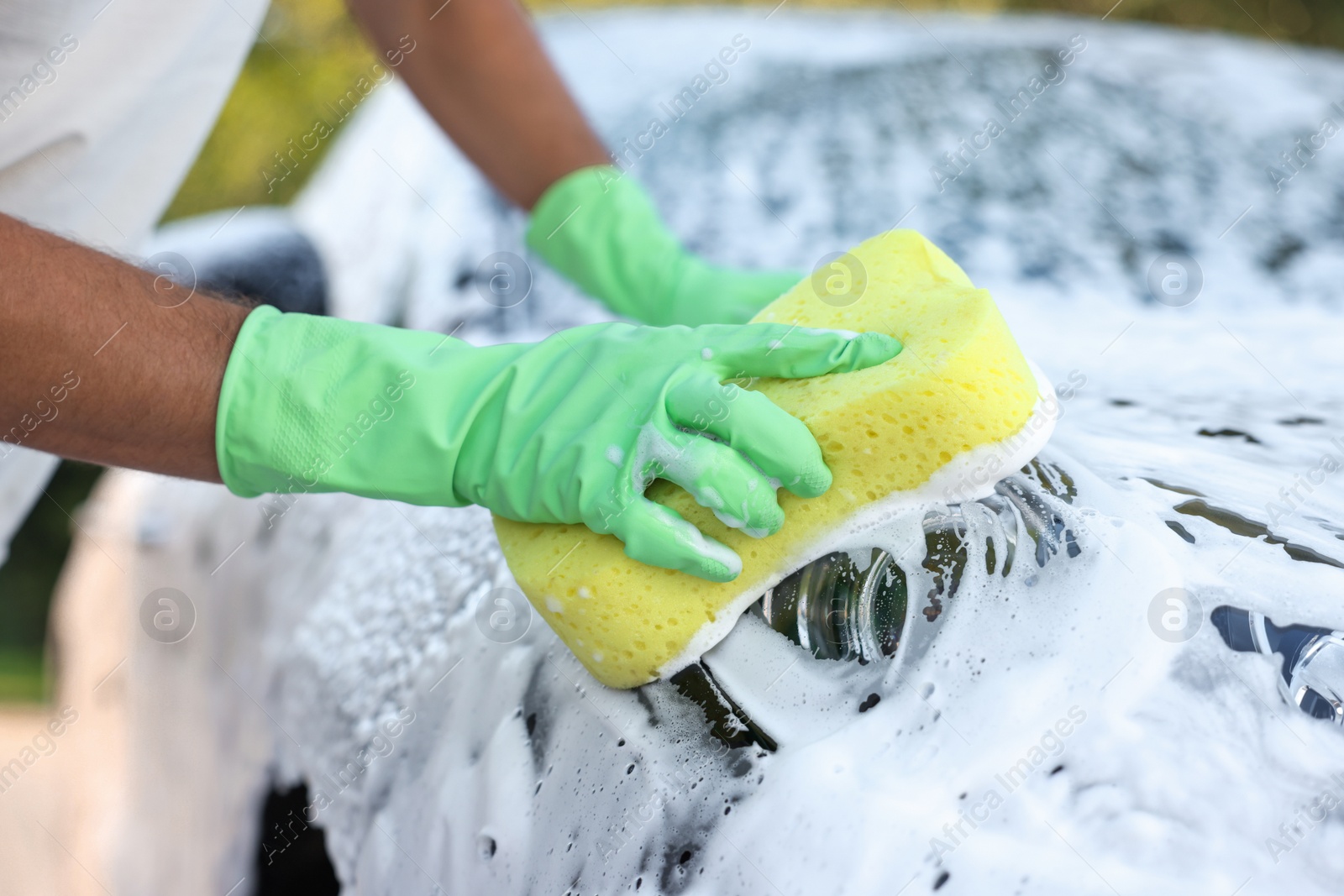 Photo of Man washing car with sponge outdoors, closeup