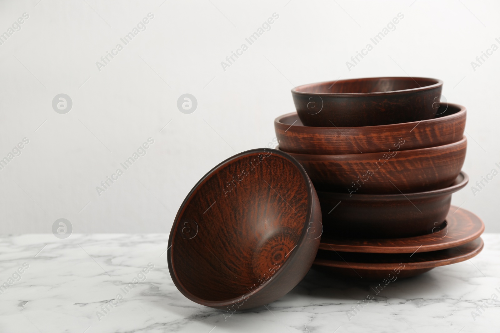 Photo of Set of clay utensils on white marble table. Space for text