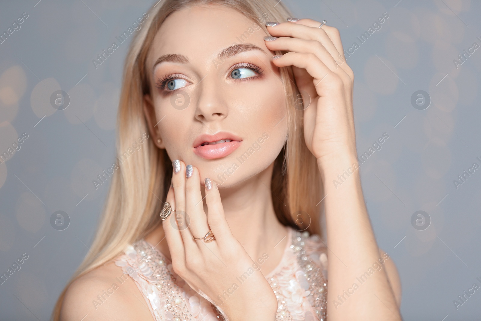 Photo of Beautiful young woman with shiny manicure on blurred background. Nail polish trends