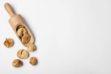 Scoop of dried figs on white background, top view with space for text. Healthy fruit