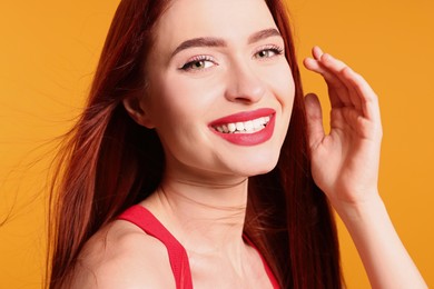 Photo of Happy woman with red dyed hair on orange background