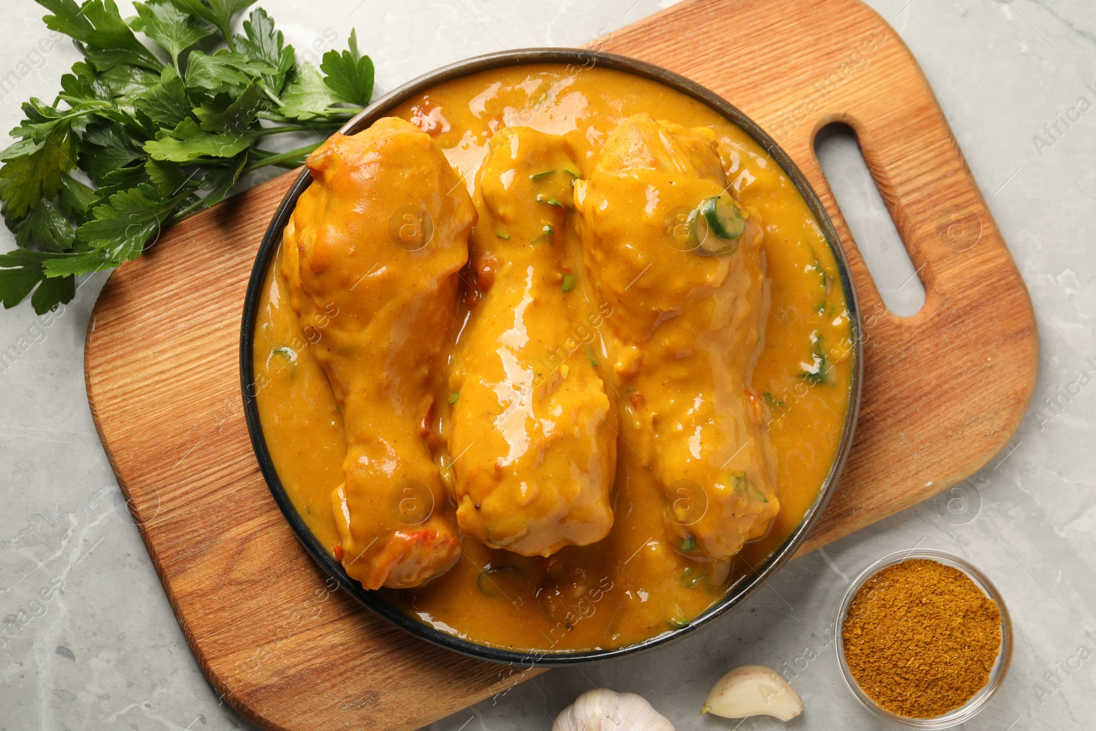 Photo of Tasty chicken curry and ingredients on grey textured table, flat lay