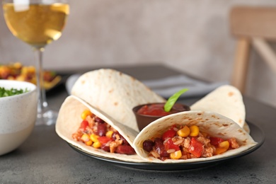 Plate with tasty chili con carne served in tortillas on gray table