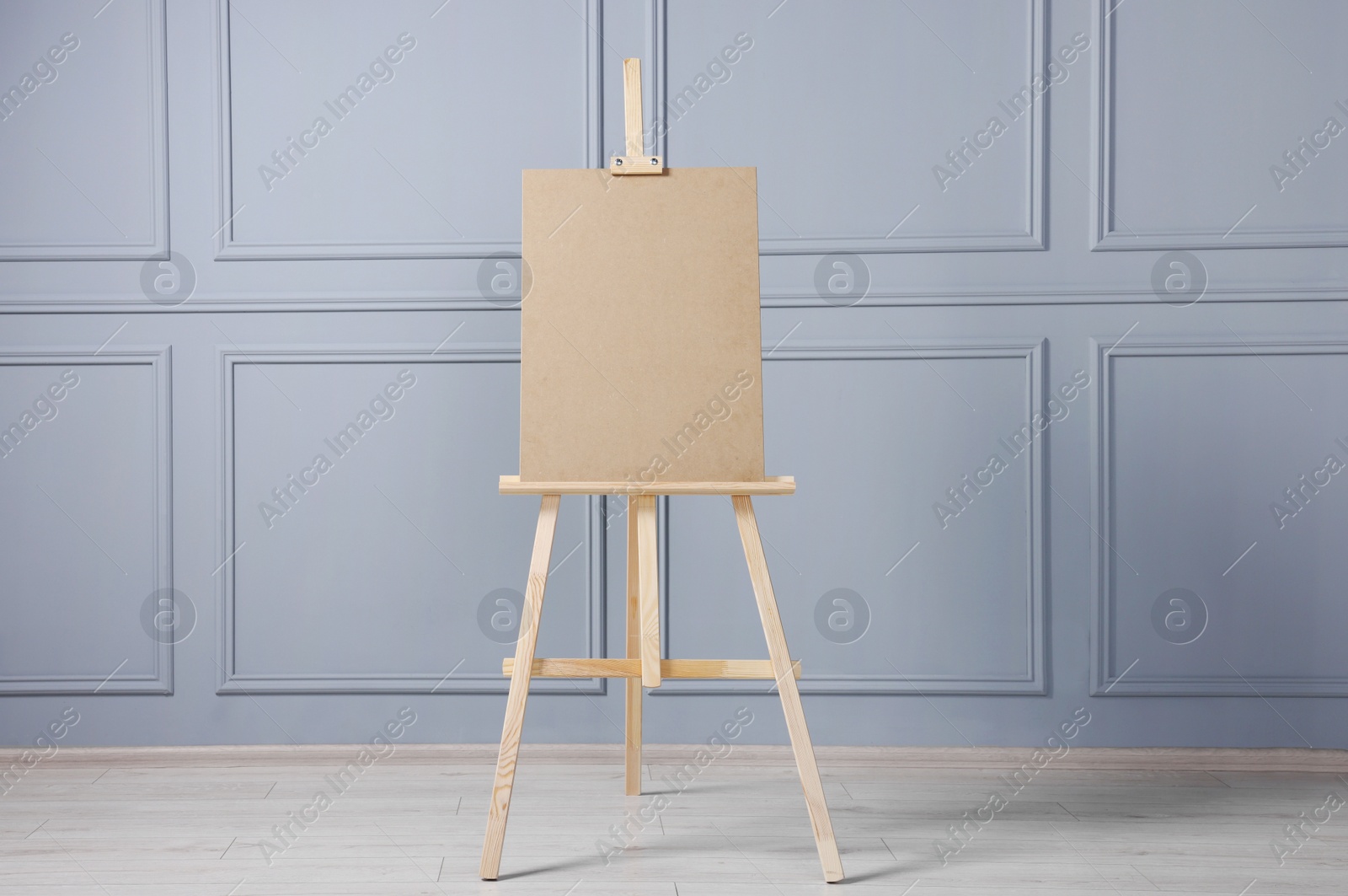 Photo of Wooden easel with blank board near grey wall indoors