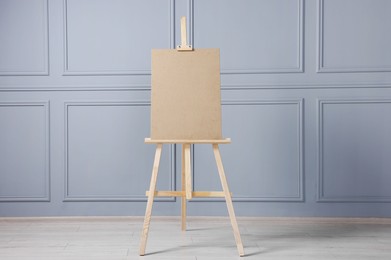 Wooden easel with blank board near grey wall indoors