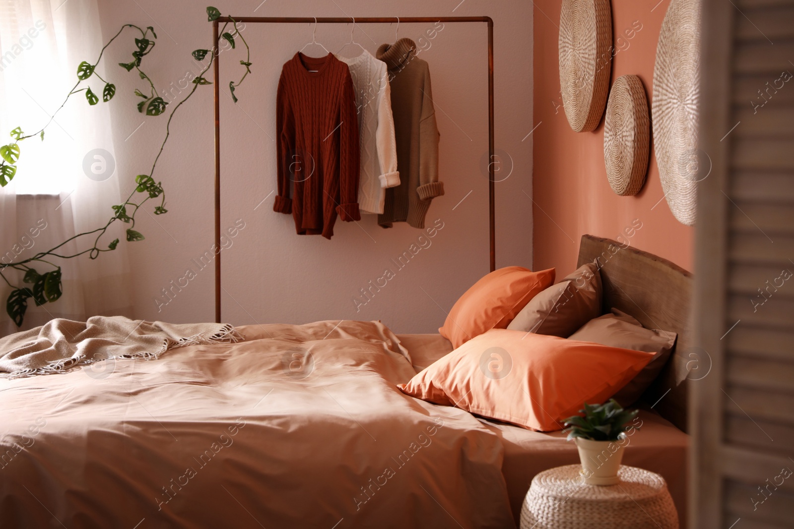 Photo of Bed with orange and brown linens in stylish room