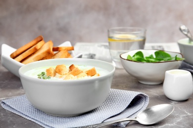 Green pea soup with croutons in bowl on table