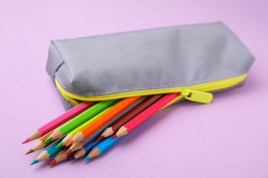 Many colorful pencils in pencil case on pink background, closeup