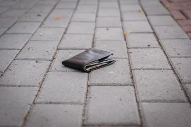 Photo of Black wallet on pavement outdoors. Lost and found