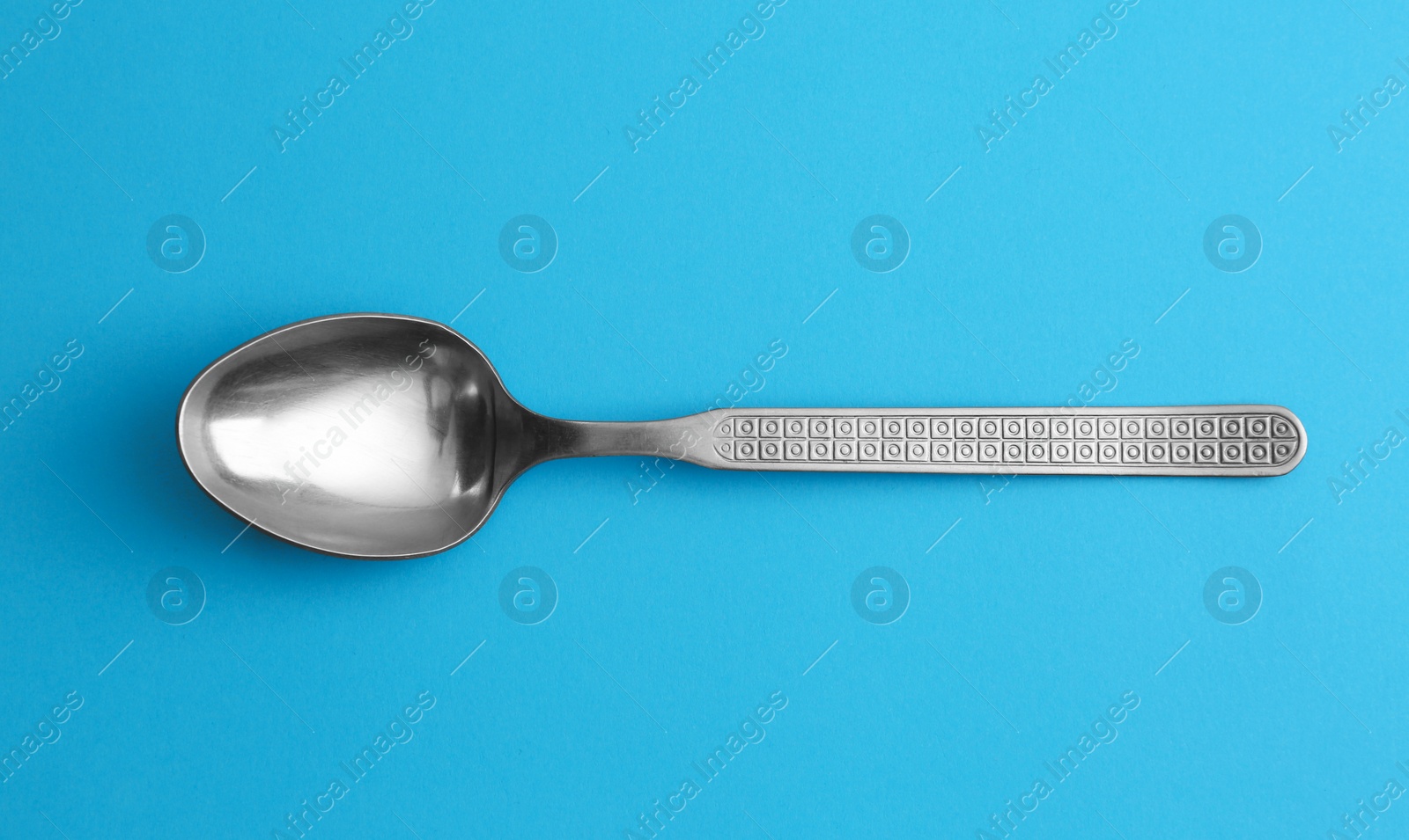 Photo of Clean empty vintage tea spoon on blue background, top view