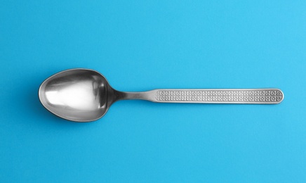 Clean empty vintage tea spoon on blue background, top view