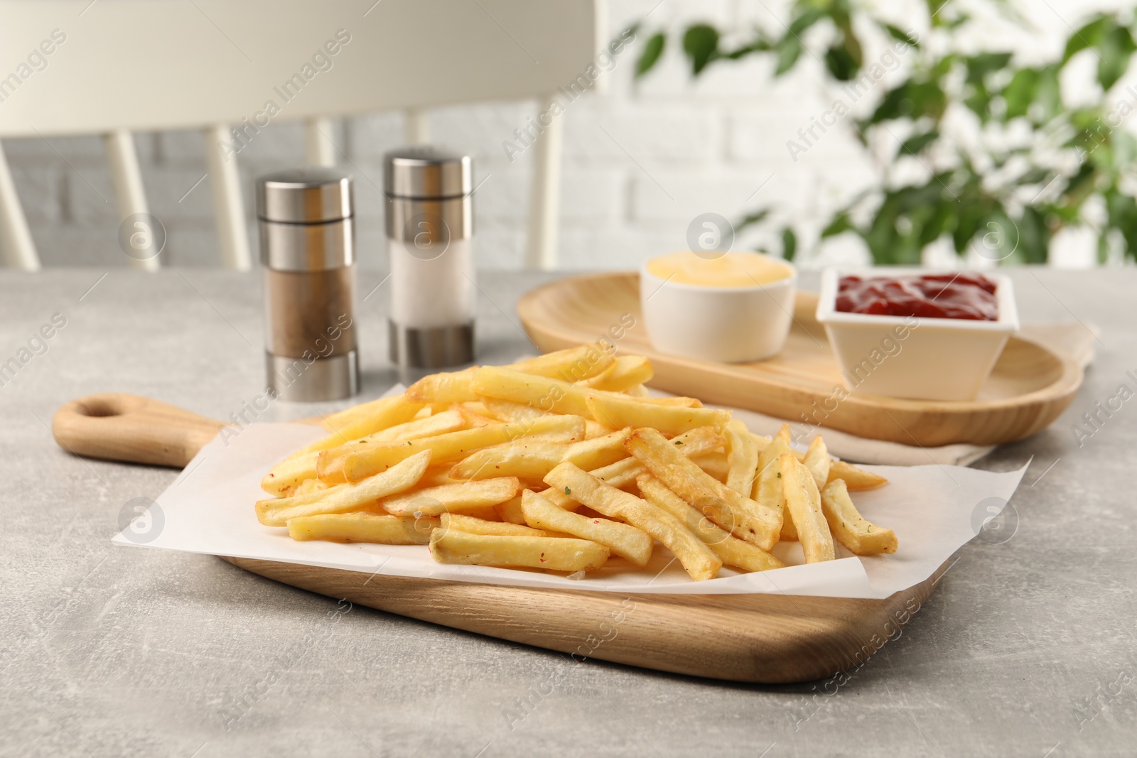 Photo of Delicious french fries served with sauces on light grey table