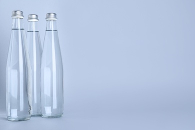 Photo of Glass bottles with water on white background, space for text